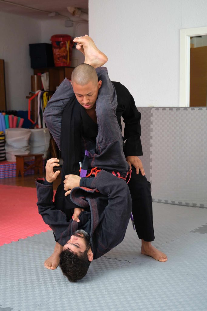Two men practicing Brazilian Jiu-Jitsu sparring at the Academy.